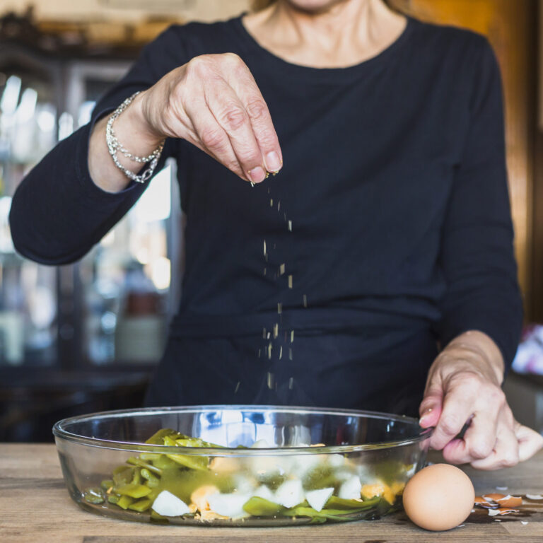 crop-hands-of-elderly-woman-sprinkling-dish-with-salt